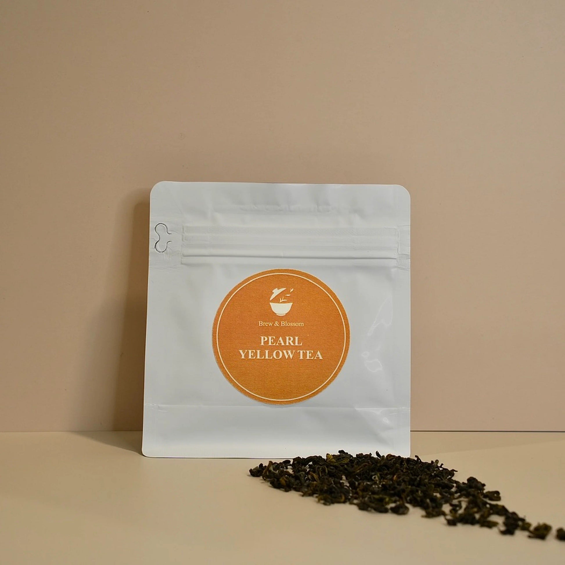 Yellow Pearl tea pouch with loose-leaf yellow tea in front
