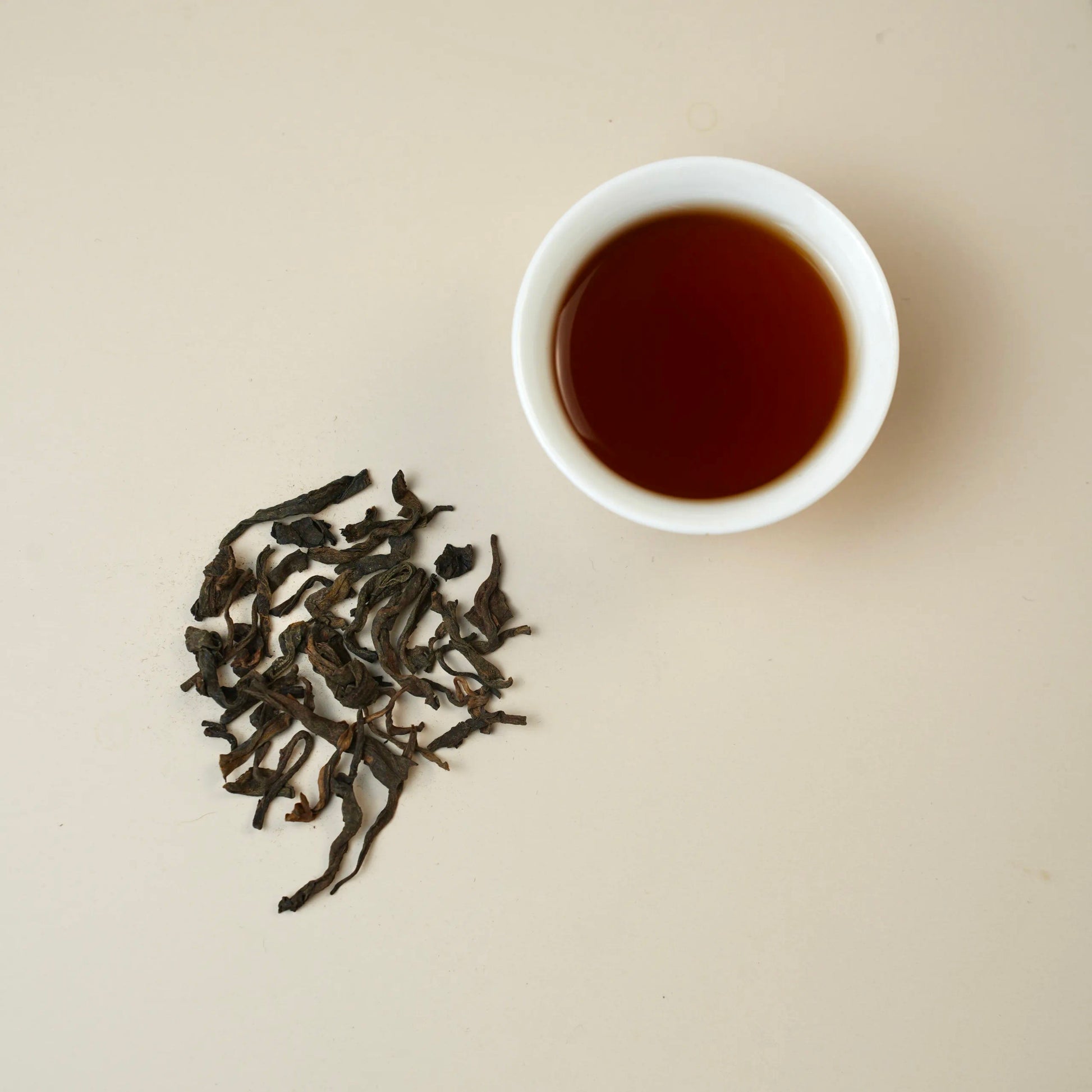 Shou Puerh Aged 10 Years dry tea leaves with brewed tea liquor in cup 